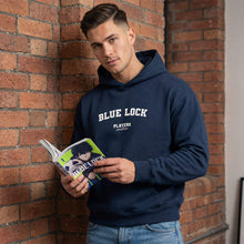 Man wearing a navy hoodie with 'Blue Lock' text, holding a book against a brick wall.