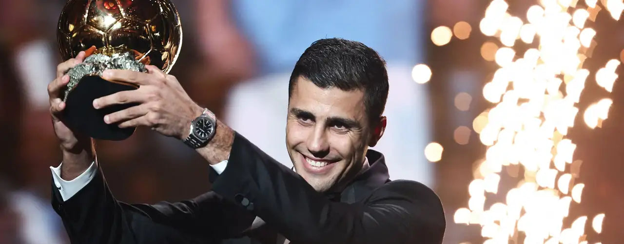 Soccer player in a black suit holding Ballon d'Or trophy with sparkling lights background