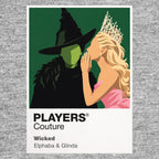Wicked Elphaba and Glinda in contrasting green, pink and black silhouettes above the land of Oz Icon Frame artwork in grey